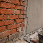 Enduit sur brique : mur fissuré avant, brosse et mortier